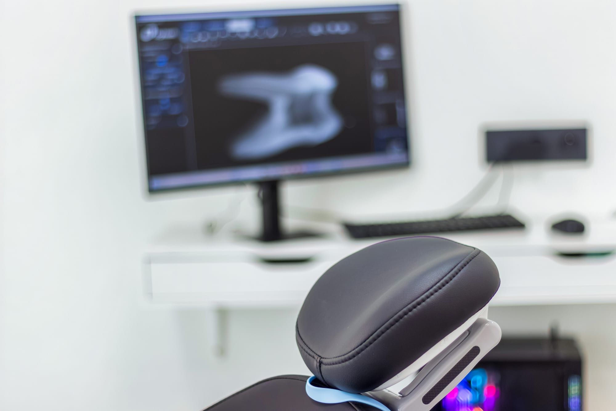 Écran affichant une radiographie dentaire numérique, derrière le fauteuil de soins