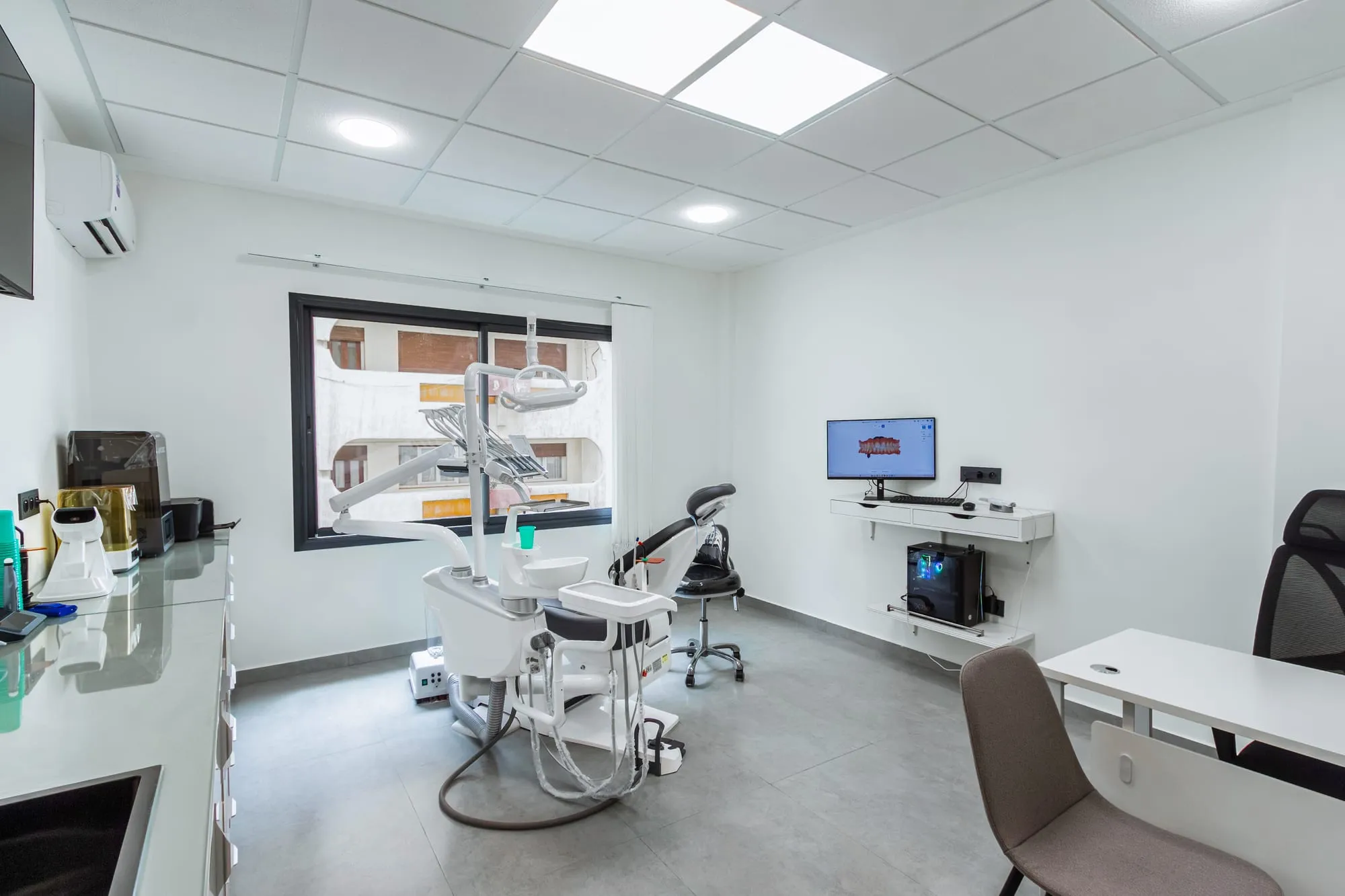 Salle de soins lumineuse, avec le fauteuil dentaire face à la fenêtre