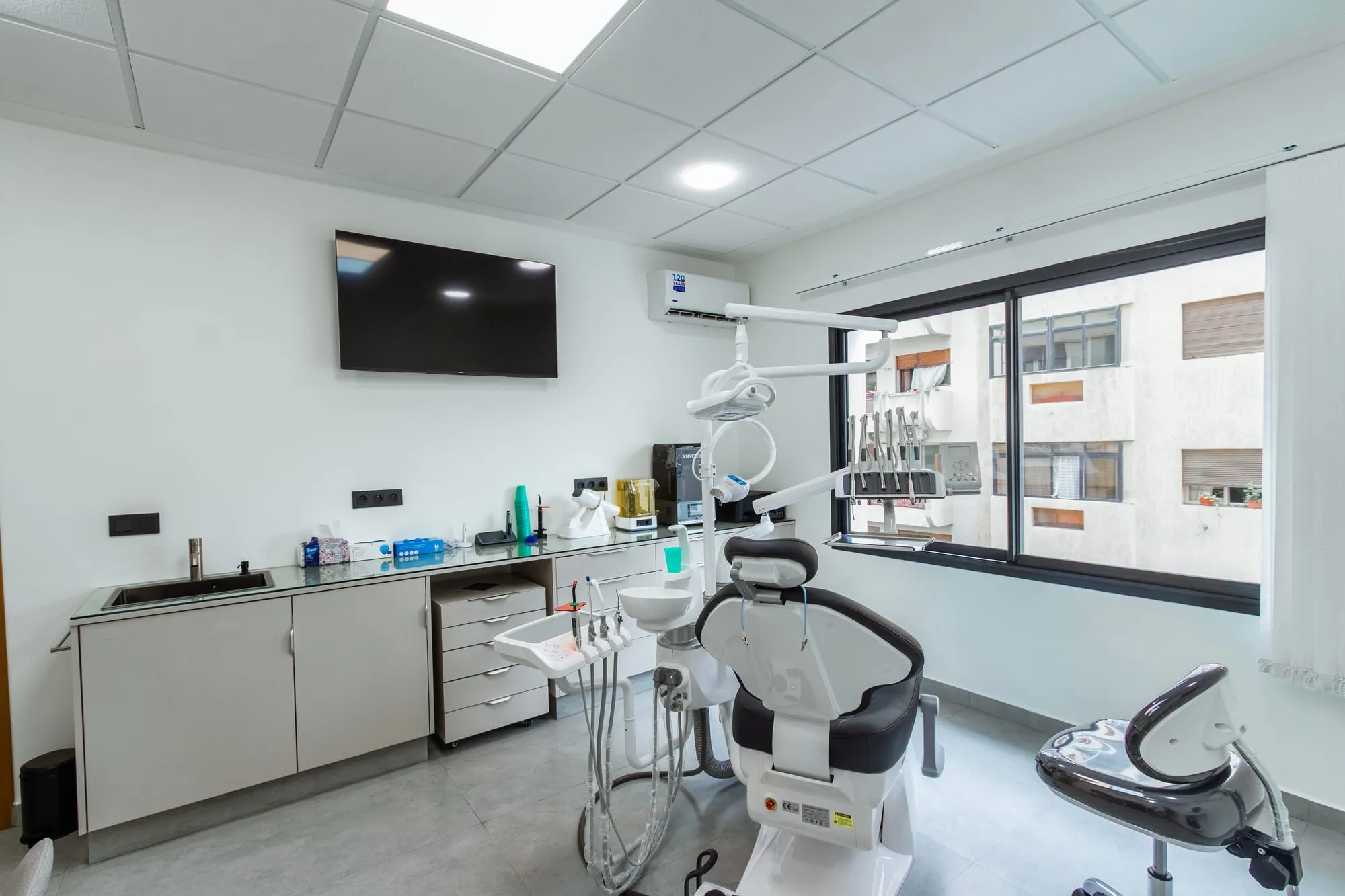 Salle de soins lumineuse du cabinet, avec le fauteuil dentaire face à la fenêtre